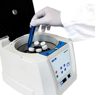 Person using a Oxford BenchMate C6V Clinical Centrifuge with a close-up of the device and gloved hand.