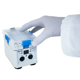 Laboratory setting with a person wearing gloves holding a sample tray above a Oxford BenchMate SPM Micro Plate Shaker.