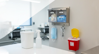 Clinic infection control setup with glove dispensers, masks, disinfectant spray, wipes canister, and wall-mounted sharps container