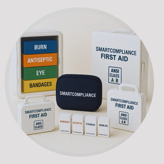 SmartCompliance wall-mount cabinet with color-coded refill boxes, portable first aid pouch, and ANSI Class A/B cabinets—clean studio background