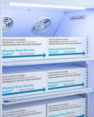 Shelves with boxes of influenza virus vaccine in a Accucold ARG3PVDL2B 3 Cu.Ft. Counter Height Vaccine Refrigerator.