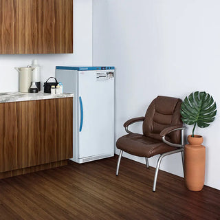 Accucold MLRS8MC 8 Cu.Ft. MOMCUBE® Breast Milk Refrigerator in a room with a brown chair and a plant.