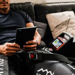 Man using the Air Relax Pro AR-4.0 on a couch while reading a tablet