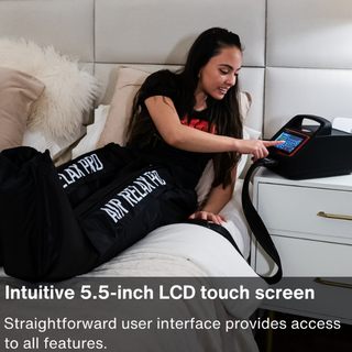 Woman wearing Air Relax Pro AR-4.0 leg sleeves in bed while using the touchscreen