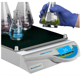 Laboratory setting with a Benchmark Scientific BT3001 Orbi-Shaker™ with Touch Screen Display, beakers, and a hand holding a beaker.