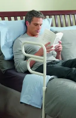 Man reading a book on a couch with a white Clarke HealtClarke Healthcare 70000 Arcorail Bedrail  in front of him