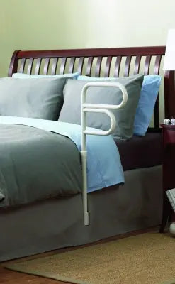 Bed with wooden headboard, gray bedding, and a white Clarke HealtClarke Healthcare 70000 Arcorail Bedrail 
