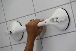 Hand using a white Clarke Healthcare R140022XS Mobeli Telescoping Shower Grab Bars on a tiled wall