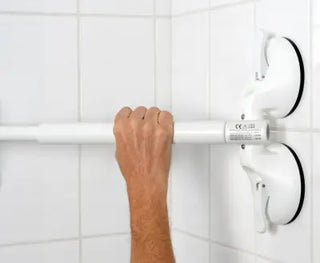 Hand holding a white Clarke Healthcare R140024XXX Mobeli QuattroPlus High Capacity Grab Bar Telescopes against a tiled wall