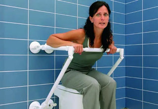 Woman using a toilet Clarke Healthcare R140026XSU Mobeli Bathtub Support Long Grab Bar in a bathroom with blue tiles.
