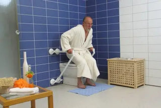 Man in a bathrobe using a toilet with a Clarke Healthcare R140026XSU Mobeli QuattroPower Support Angle Adjustable Grab Bar  in a bathroom.