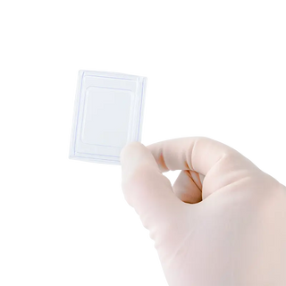 Hand wearing a glove holding a small white square Dynarex Disposable Base Mold against a white background