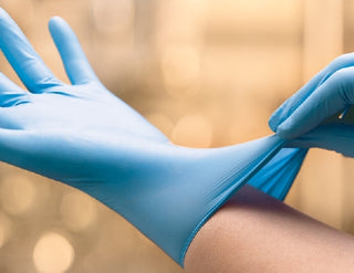 Person wearing ESTEEM™ Stretch 802186_CS, Nitrile Exam Glove, Small,Standard Cuff, Textured Fingertips,Teal against a blurred beige background