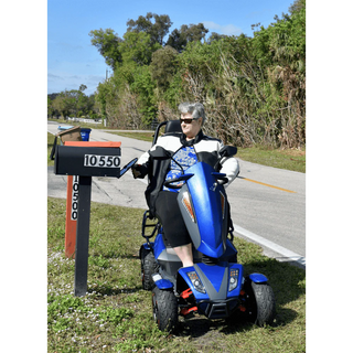 Person using a blue mobility scooter on a road with trees and a mailbox in the background