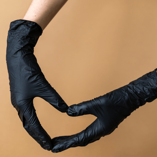 Hands in black Eco Gloves Nitrile Exam Gloves pulling a glove over the wrist