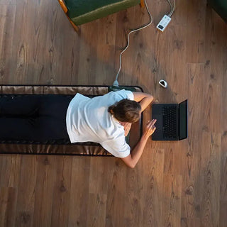 Person lying on the HealthyLine Mesh JT mat while using a laptop