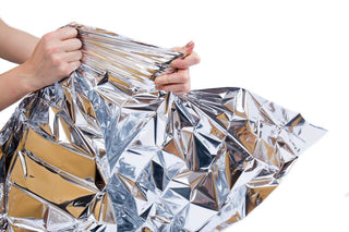 Hands unfolding a silver HealthyLine mylar blanket