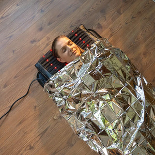 Woman wrapped in a HealthyLine mylar blanket on a heating mat