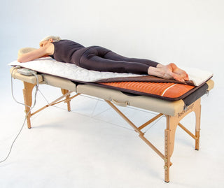 Person lying on a HealthyLine mat covered with the padded cover on a table