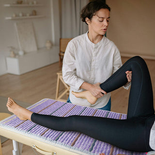 Woman seated on a HealthyLine Platinum mat on a massage table