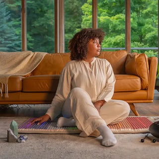 Woman on a sofa with her feet on a HealthyLine Rainbow Chakra mat