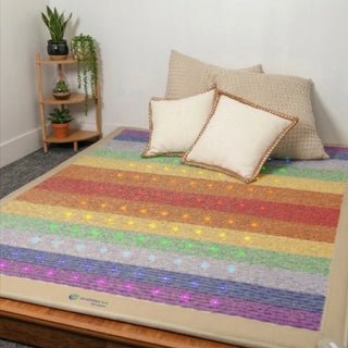 Queen-size HealthyLine Rainbow Chakra mat on a bed