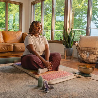Woman meditating on a HealthyLine Rainbow Chakra mat in a living room
