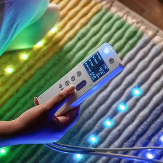 Hand holding the controller over the lit HealthyLine Rainbow Chakra mat