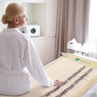 Woman in a robe sitting on the HealthyLine SOFT mat in a spa room