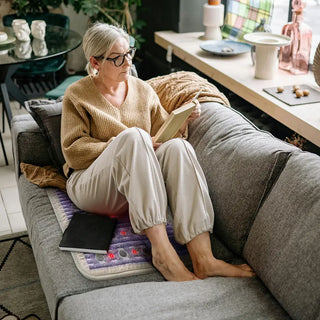Woman reading on a sofa beside the medium HealthyLine TAJ mat