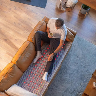 Man sitting on a sofa on the full-length HealthyLine TAJ mat