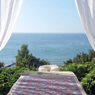 HealthyLine TAJ Pro Plus mat on an outdoor spa table facing the ocean