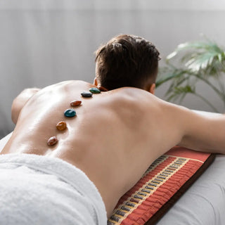 Man lying face down on a HealthyLine TAO mat during a hot stone session