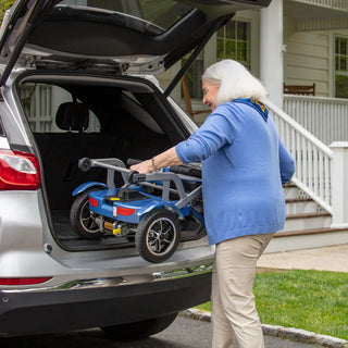 An older woman loading a folded Journey So Lite 08474 scooter into the trunk of an SUV.