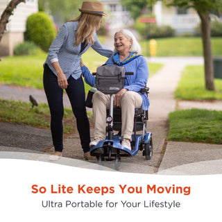 An older woman seated on a Journey So Lite 08474 scooter on a pavement beside a friend in a hat.