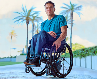 Man in a wheelchair with Ki Mobility Klaxon Twist (E0986) with palm trees in the background