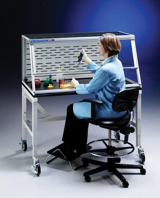 Person in a lab coat working at a Labconco 5 Feet Protector XVS Ventilation Station, 22.8 Inch High, 115V or 230V, 50-60Hz with various bottles and equipment.