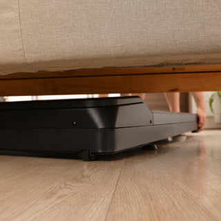 Lifespanfitness TR1200BPro-SC130 Omni GlowUp Under Desk Treadmill on a wooden floor with a couch in the background