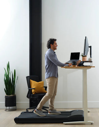 Man using a Lifespanfitness TR5000BPro-SC130 Omni GlowUp Under Desk Treadmill in a home office setting.