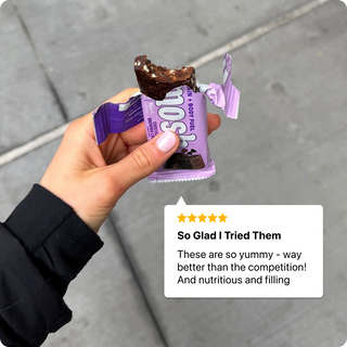 Hand holding a bitten MOSH protein bar beside a customer review