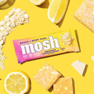 Wrapped MOSH Lemon White Chocolate Crunch Protein Bar surrounded by its flavor ingredients