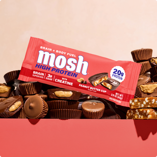 Wrapped MOSH Peanut Butter Cup High Protein Bar resting on chocolate peanut butter cups
