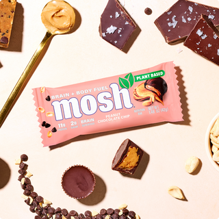 Wrapped MOSH Peanut Chocolate Chip Plant-Based Protein Bar surrounded by its flavor ingredients