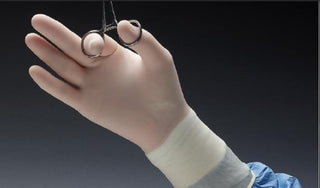 Hand wearing Protexis™ PI Micro 671225_CS, Surgical Glove, Size 7.5, Polyisoprene, Standard Cuff, Cream holding a pair of forceps against a dark background