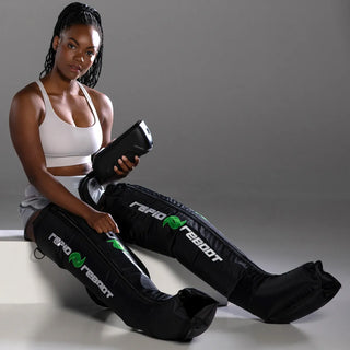 Woman seated wearing Rapid Reboot compression boots and holding the REGEN control unit