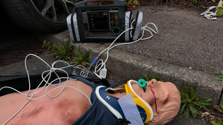 Mannequin with medical equipment on the ground next to a car