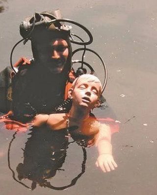 Person in scuba gear holding a child underwater
