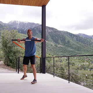 Man exercising with Stroops FSPALB Fit Stik Pro Bar and resistance bands on a balcony with mountain views