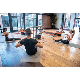 The Stroops CONNECTUS is a black and gray circular steel fitness training system with a round barre at the top and six vertical anchor spines arranged around the base. Each spine provides multiple connection points for resistance bands, allowing up to six people to perform full-body training around the system.
