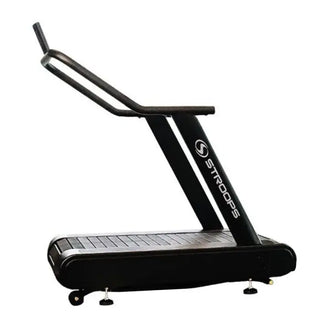 A black flat self-propelled motorless treadmill with a low-profile steel frame, slatted running belt, front support handles, and a vertical steel spine positioned behind the treadmill. The system can be configured with optional resistance training accessories including the Base Slastix® Adjustable Anchor, Universal Swivel Belt XL, and Optitail® Anchoring System for performance training and rehabilitation applications.